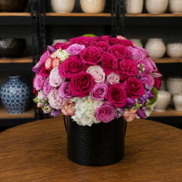 Round bouquet of pink and purple roses in a black vase
