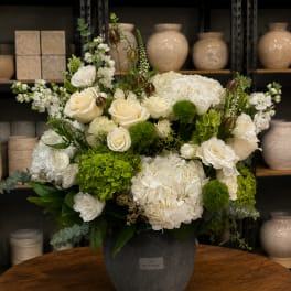 White floral arrangement in a dark vase with green accents