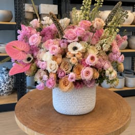 Large pastel bouquet of roses and mixed blooms in a white textured vase