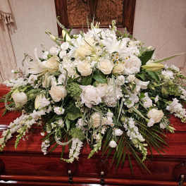 Large white floral spray on a polished wooden casket