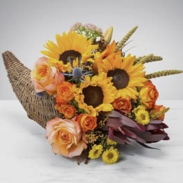 Bouquet of sunflowers and orange roses in a woven horn-shaped basket