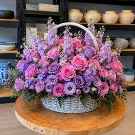 Basket of pink and lavender roses with purple flowers