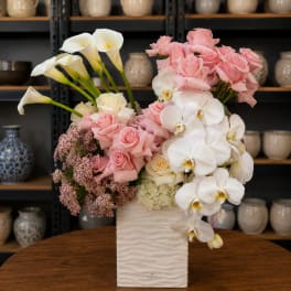 Pink roses and white orchids in a white vase with calla lilies