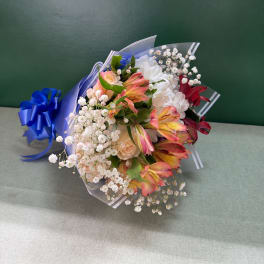 Bouquet of pink and white flowers wrapped in blue paper with a ribbon