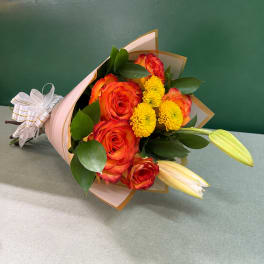 Bouquet of orange roses and yellow mums wrapped in pink paper