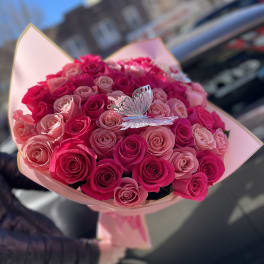 Bouquet of pink and hot pink roses with a butterfly pick