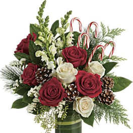 Red and white roses in a green glass vase with candy canes and pinecones