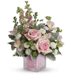 Pink roses and mixed blooms in a clear square vase