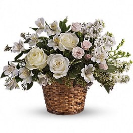 White roses and small white flowers in a woven basket