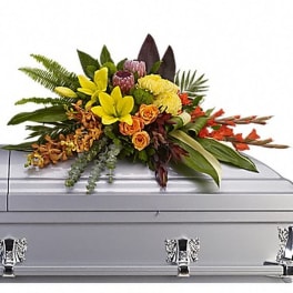 Floral casket spray with yellow, orange, and red blooms on a silver casket