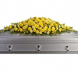 Yellow floral casket spray on a gray coffin