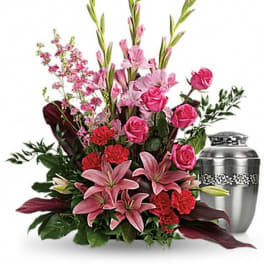 Pink lilies and roses arranged beside a silver urn