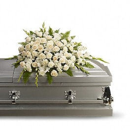 White floral casket spray on a gray coffin