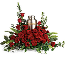 Red roses arranged around a silver urn with greenery
