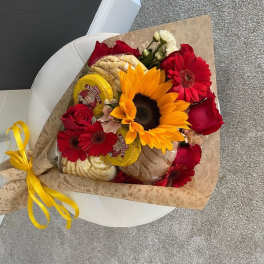 Bouquet of red roses and sunflowers with packaged bread and a yellow ribbon