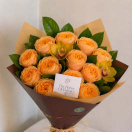 Bouquet of peach roses with yellow orchids wrapped in brown paper