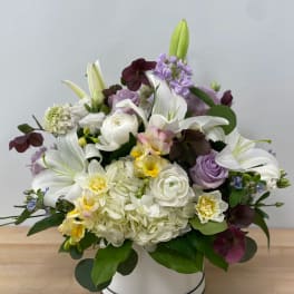 Mixed bouquet of white lilies, roses, and hydrangeas in a white hat box