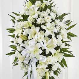 White funeral spray with lilies, roses, and chrysanthemums on a stand
