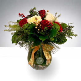 Red and white roses arranged in a glass vase with gold ribbon
