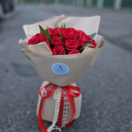 Bouquet of red roses wrapped in beige paper with a red ribbon