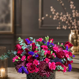Bright pink and red flower arrangement in a patterned black box