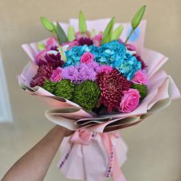 Bouquet of pink roses, blue hydrangeas, and purple chrysanthemums wrapped in pink paper