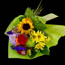 Colorful mixed bouquet with sunflowers, daisies, and carnations wrapped in green paper