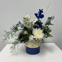 Blue and white floral arrangement in a round blue container