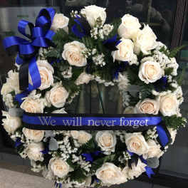 White rose funeral wreath with blue ribbon on an easel