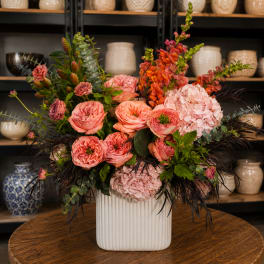 Pink and coral floral arrangement in a white ribbed vase