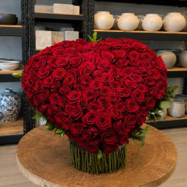 Large heart-shaped arrangement of red roses on a round wooden table