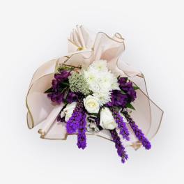 Bouquet of white and purple flowers wrapped in pale pink paper