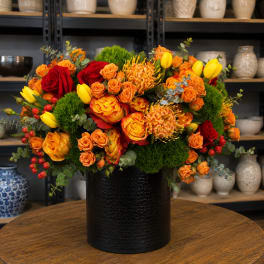 Bouquet of red and orange roses with yellow tulips in a black vase