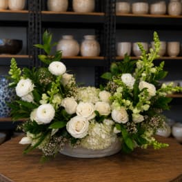 White roses and ranunculus arranged in a low ceramic bowl