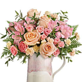 Pink and peach roses with pink lilies in a ceramic pitcher vase