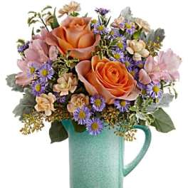 Peach roses and purple daisies in a turquoise mug vase