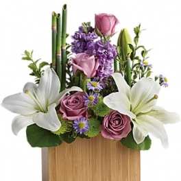 Purple and white floral arrangement in a wooden box with lilies and roses