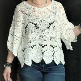 Person wearing a white lace top and blue jeans against a dark background