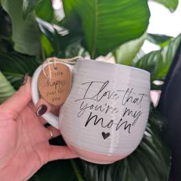 White mug with "I love that you're my mom" text and a hanging tag