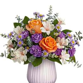 Orange and purple mixed bouquet in a ribbed glass vase