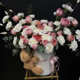 Pink and white roses with carnations in a white hatbox, with a teddy bear attached