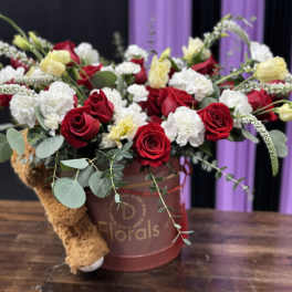 Red roses and white carnations in a pink hatbox with a teddy bear