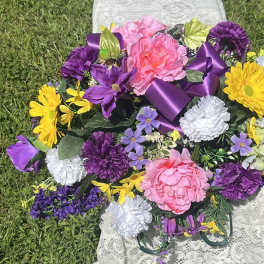 Colorful bouquet with pink, purple, yellow, and white flowers tied with a purple ribbon