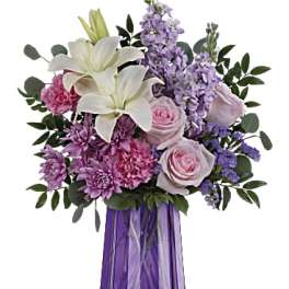Bouquet of white lilies, pink roses, and purple flowers in a purple vase