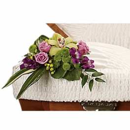 Purple and green floral spray on a white casket