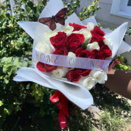 Bouquet of red and white roses wrapped in white paper with a butterfly decoration