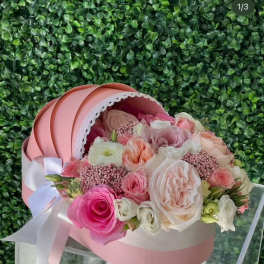 Pink and cream rose bouquet in a round hatbox with a ribbon