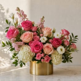 Pink and peach roses with white blooms in a gold vase