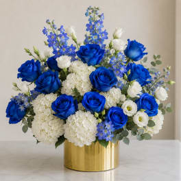Blue roses and white blooms arranged in a gold vase