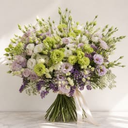 Large bouquet of white, lavender, and green flowers tied with a ribbon